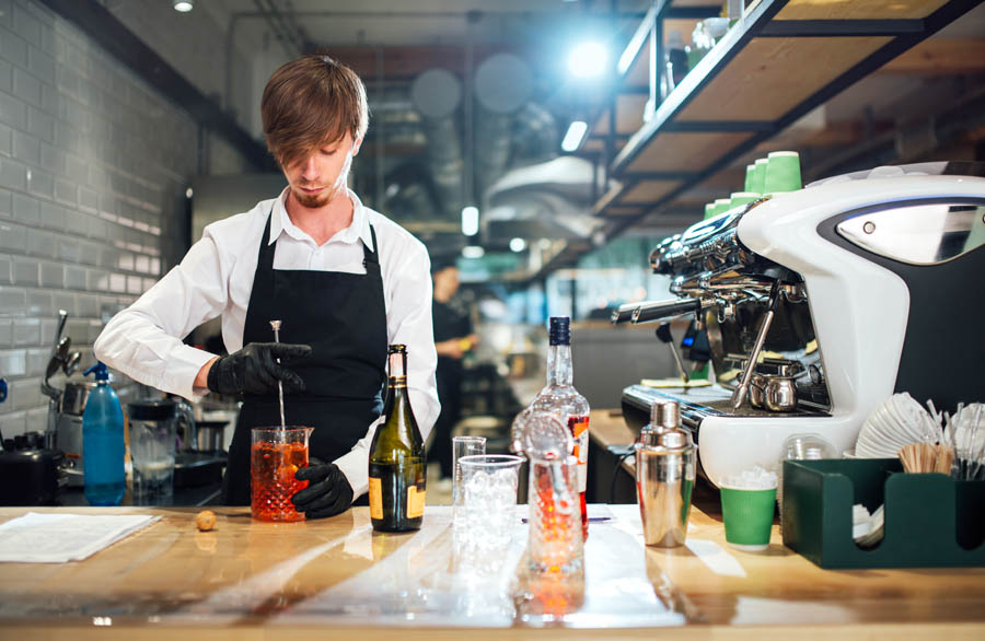 Barman stirring the cocktail with a bar spoon. Professional drink preparation process.